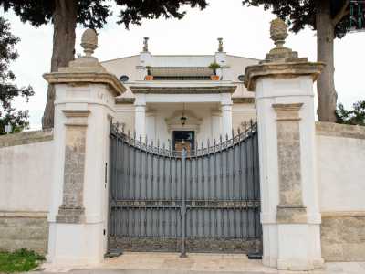 Siamo quindi davanti all�ingresso della tenuta, posta su una piccola altura e introdotta da un alto cancello grigio incastonato tra due alte colonne in pietra sovrastate da pigne decorative